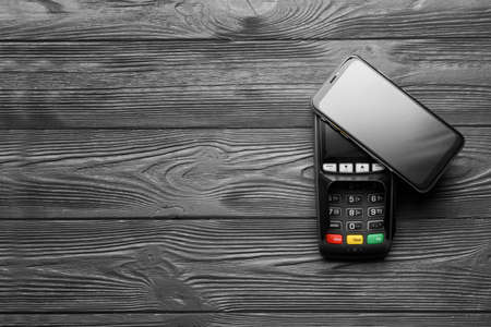 Payment terminal with mobile phone on dark wooden backgroundの写真素材