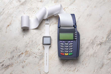 Payment terminal with smart watch on light background