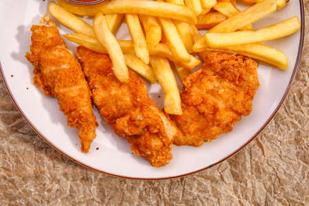 Tasty french fries with deep fried chicken wings on plate, closeupの写真素材