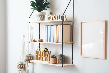 Shelf with books and decor hanging on light wall
