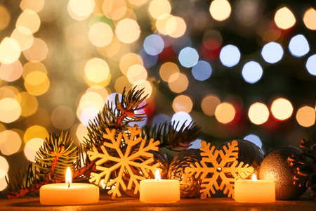 Christmas composition with decor and candles on table against blurred lights
