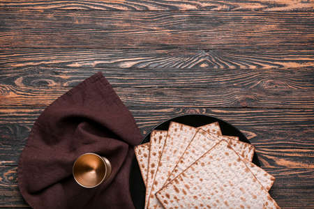 Plate with Jewish flatbread matza for Passover and cup on wooden backgroundの写真素材