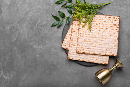 Jewish flatbread matza for Passover and cup on gray background