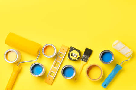 Cans of paints and tools on color backgroundの写真素材