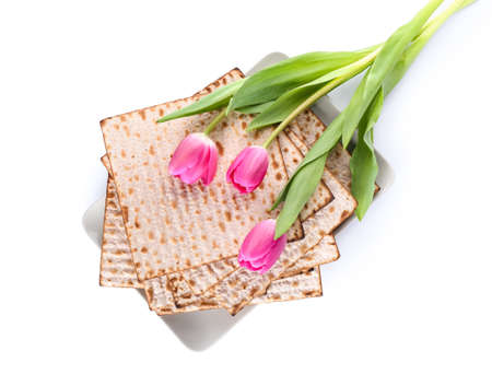 Jewish flatbread matza for Passover and flowers on white background