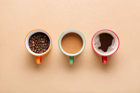 Cups of hot coffee and beans on color backgroundの写真素材