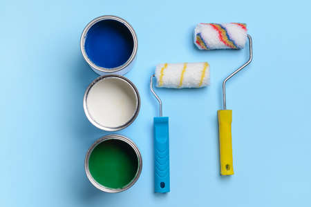 Cans of paints and rollers on color backgroundの写真素材