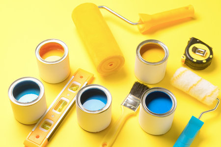 Cans of paints and tools on color backgroundの写真素材