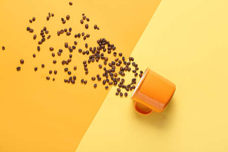 Composition with cup and coffee beans on color backgroundの写真素材