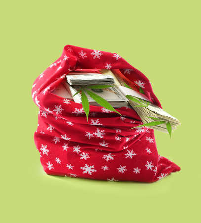 Santa Claus bag full of money and hemp leaves on green backgroundの写真素材