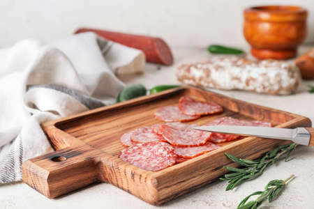 Board with slices of salami on tableの写真素材