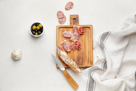 Board with slices of salami on light backgroundの写真素材