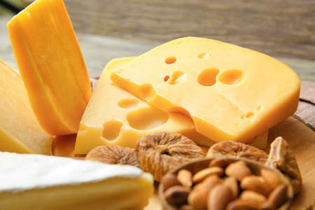 Tasty cheese, nuts and dried figs on wooden background, closeupの写真素材