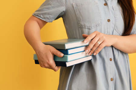 Woman with stack of books on color backgroundの写真素材
