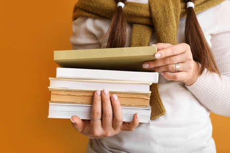 Woman with stack of books on color background, closeupの写真素材
