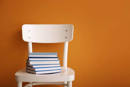 Chair with stack of books on color backgroundの写真素材