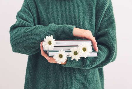 Woman holding books with fresh flowers, closeup