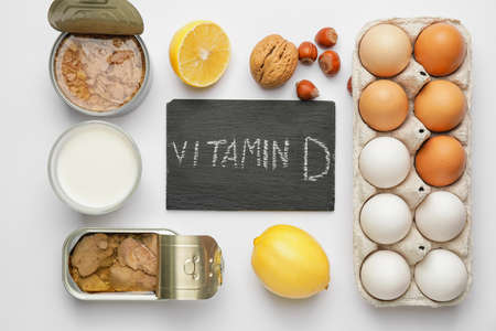 Text VITAMIN D and different healthy products on white background