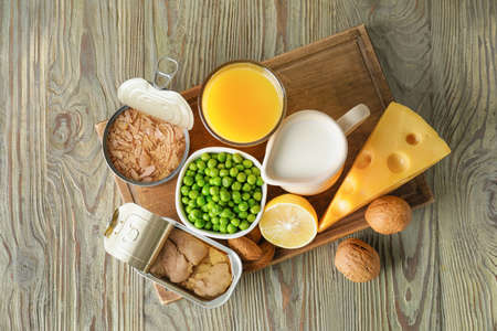 Different healthy products with vitamin D on wooden background