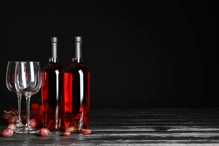 Glasses and bottles of wine on dark background
