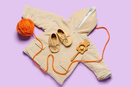 Stylish baby clothes with toy and knitting yarn on color backgroundの写真素材