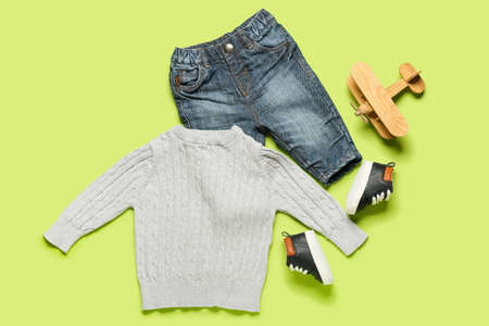 Stylish baby clothes with toy on color background