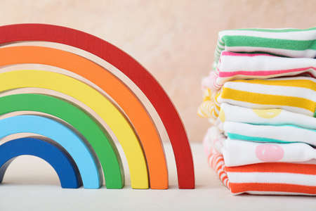 Stylish baby clothes with rainbow on color backgroundの写真素材