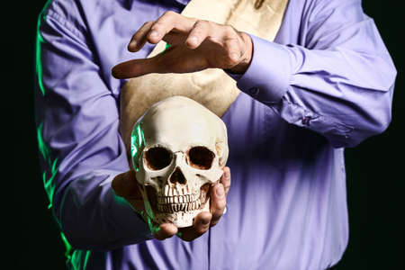 Male fortune teller with human skull on dark background, closeupの写真素材