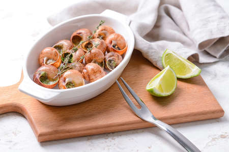 Baking dish with tasty snails on light backgroundの写真素材