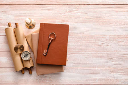 Old books, compass, scrolls, key and candle on color wooden background