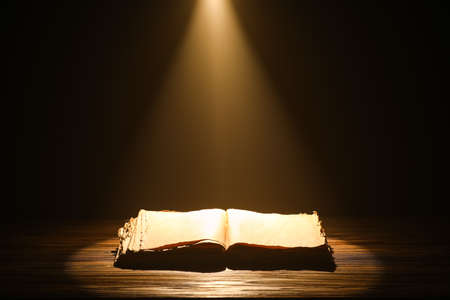 Open old book on table against dark backgroundの写真素材