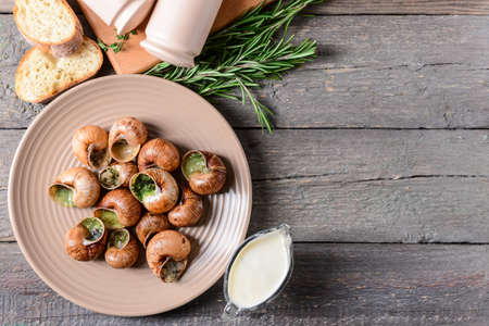 Plate with tasty snails on wooden backgroundの写真素材