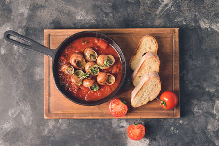 Frying pan with tasty snails on grunge backgroundの写真素材