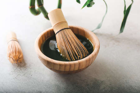 Bowl with matcha tea and chasens on light backgroundの写真素材