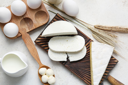 Different dairy products and chicken eggs on light background