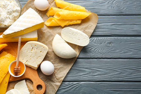 Different dairy products, chicken eggs and honey on dark wooden background