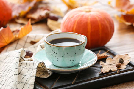Beautiful autumn composition with cup of coffee and pumpkins on wooden background, closeupの写真素材