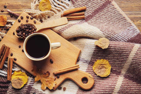 Board with cup of coffee, cinnamon sticks and beans on wooden backgroundの写真素材