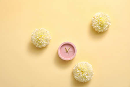Alarm clock with flowers on color background