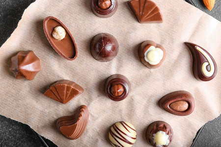 Parchment with tasty chocolate candies on dark background