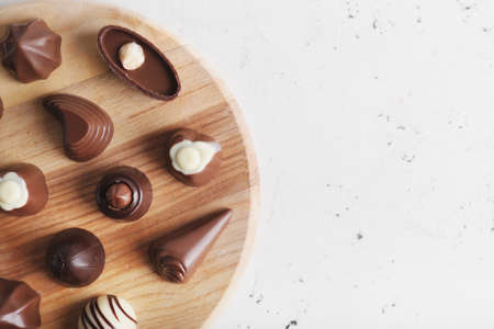 Board with tasty chocolate candies on white backgroundの写真素材