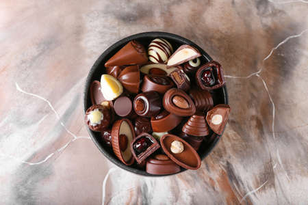 Bowl with tasty chocolate candies on grunge backgroundの写真素材