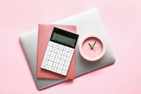 Alarm clock with calculator, notebook and laptop on color backgroundの写真素材