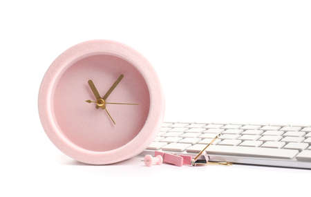 Alarm clock with office supplies and computer keyboard on white background