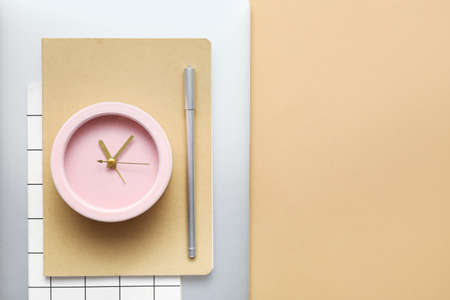 Alarm clock with office supplies and laptop on color background