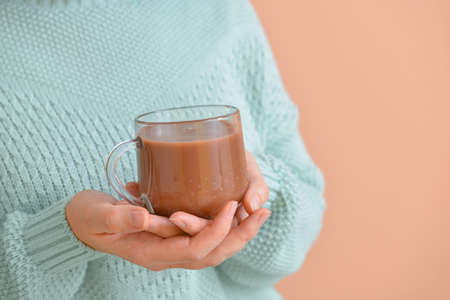 Young woman with hot cocoa on color background, closeupの写真素材