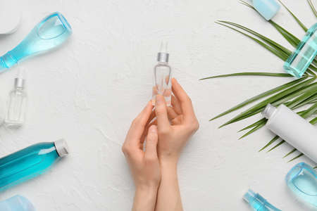 Woman holding bottle of cosmetic product on light background