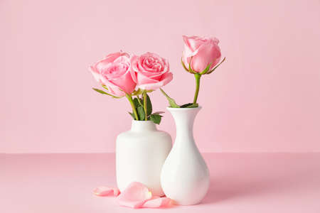 Beautiful pink roses in vases on color backgroundの写真素材