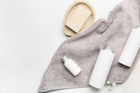 Bottles of cosmetic products, soap and towel on light backgroundの写真素材