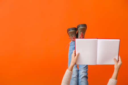 Cute little girl with book on color background